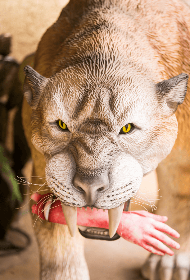 a large tan cat with extremeley long
             fangs, yellow eyes and what appears to be a bloody, dismembered human forearm
             and hand in its mouth.